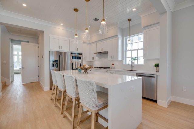 kitchen with a kitchen island, pendant lighting, sink, white cabinets, and stainless steel appliances