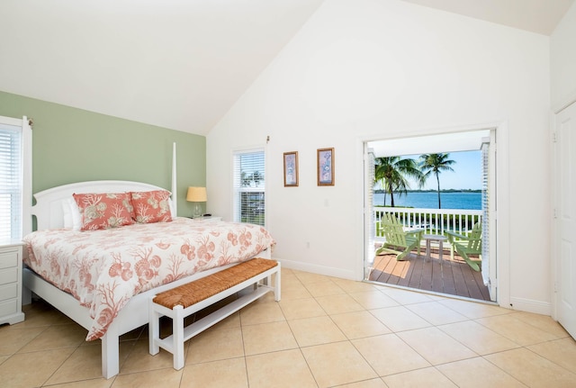 bedroom featuring multiple windows, light tile patterned floors, access to outside, and a water view