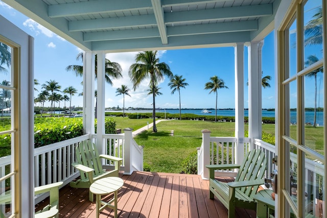 wooden terrace featuring a water view and a yard