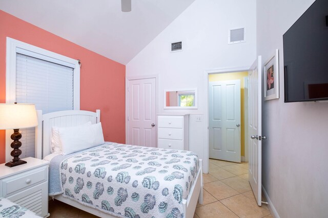 bedroom with high vaulted ceiling, light tile patterned floors, ceiling fan, and a closet