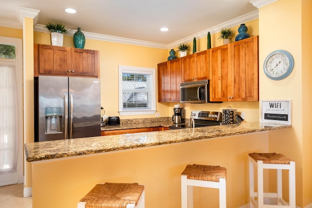 kitchen with stainless steel appliances, light stone counters, a kitchen breakfast bar, and kitchen peninsula