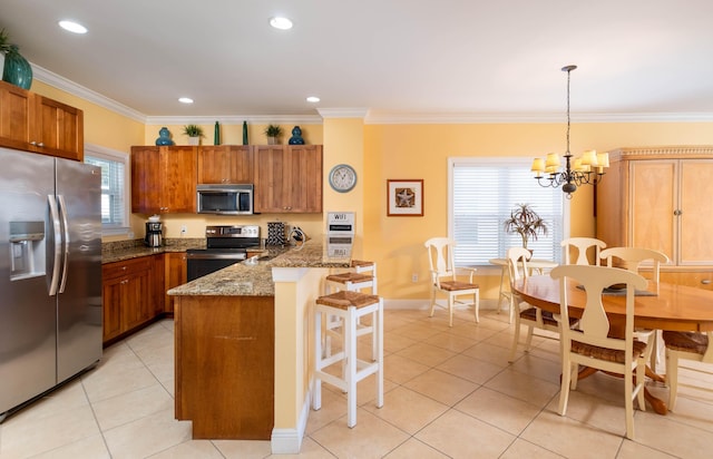 kitchen featuring appliances with stainless steel finishes, a kitchen bar, hanging light fixtures, crown molding, and light stone countertops