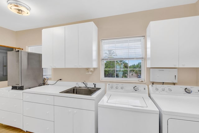 clothes washing area with cabinet space, washing machine and dryer, and a sink