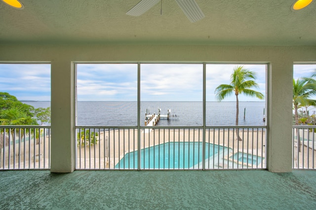 unfurnished sunroom with a water view and a ceiling fan