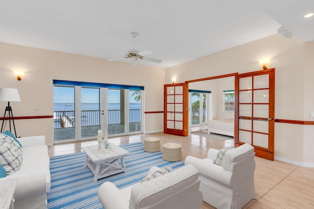 tiled living area featuring french doors, a ceiling fan, and baseboards