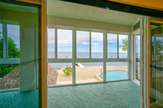 unfurnished sunroom featuring a water view, plenty of natural light, and ceiling fan