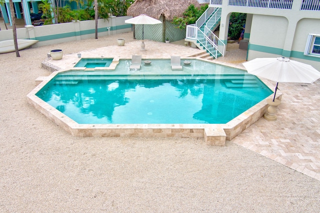 view of swimming pool featuring stairs, a patio, fence, and a pool with connected hot tub