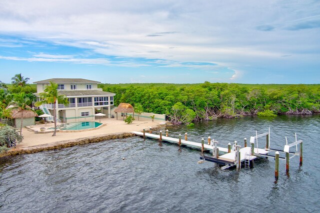 dock area with a water view, a patio, fence, an outdoor pool, and boat lift