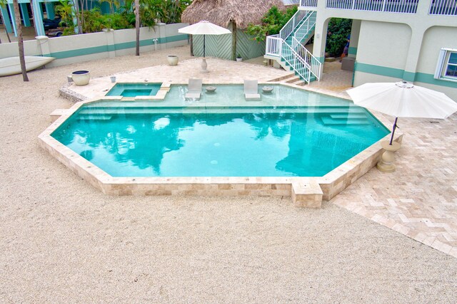 view of swimming pool featuring a patio, an in ground hot tub, stairs, and fence