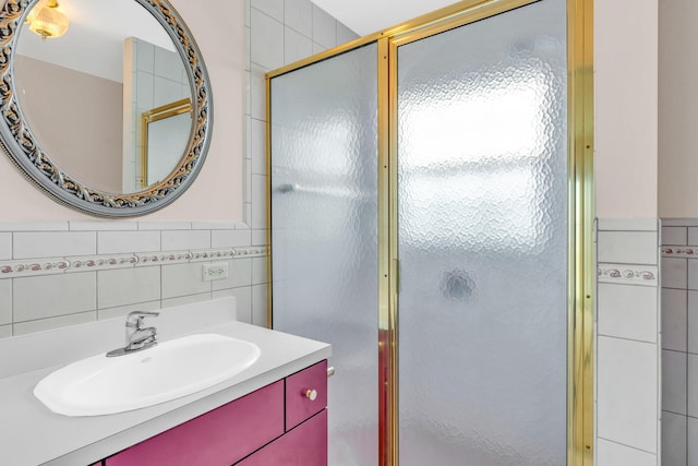 bathroom featuring vanity, a shower with shower door, and tile walls