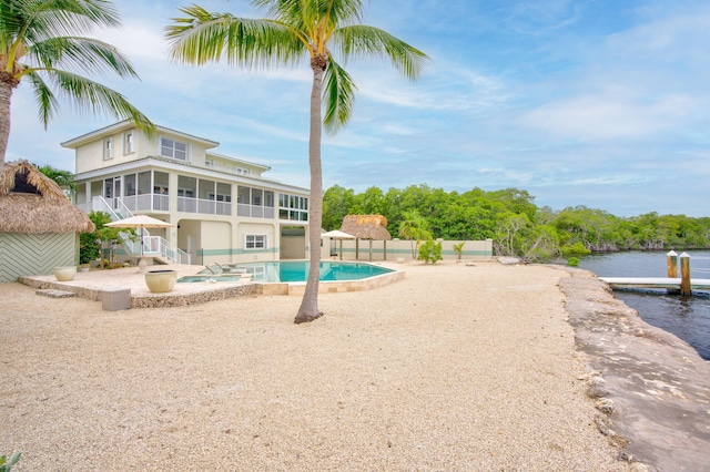 outdoor pool featuring fence, a water view, a patio, and a sunroom