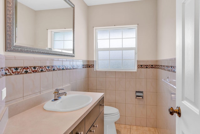 bathroom with toilet, tile walls, wainscoting, tile patterned flooring, and vanity