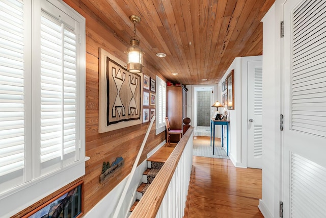 hallway with recessed lighting, wooden walls, an upstairs landing, wood finished floors, and wooden ceiling