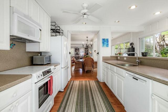 kitchen with white appliances, dark wood-style flooring, a sink, and white cabinetry