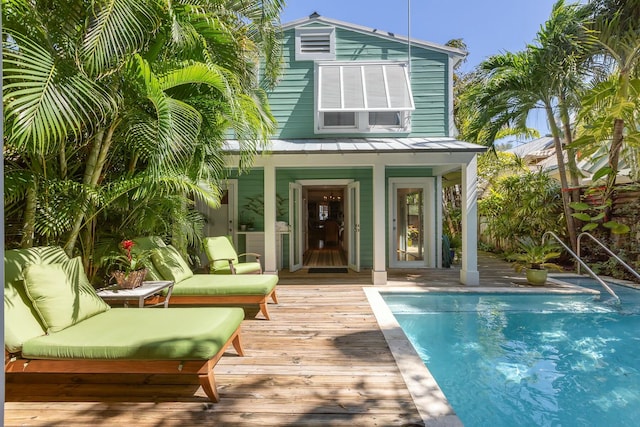 back of house with an outdoor pool, a standing seam roof, metal roof, and an outdoor living space