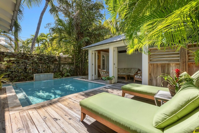 view of pool featuring a fenced in pool, fence, a deck, an outdoor structure, and an outdoor living space