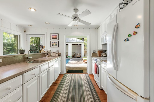 kitchen with dark wood finished floors, white appliances, white cabinetry, and a sink