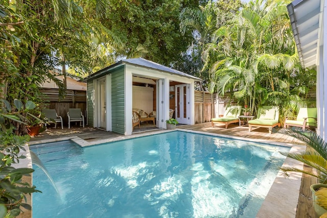 view of swimming pool with an outdoor structure, an exterior structure, a fenced in pool, and fence