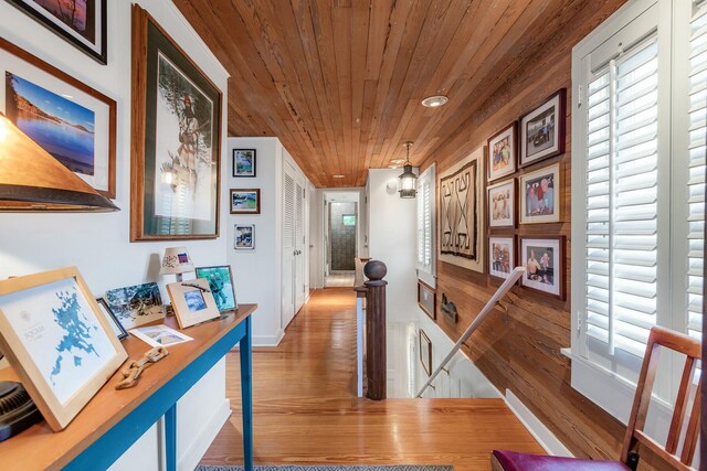 corridor featuring wooden ceiling, an upstairs landing, and wood finished floors