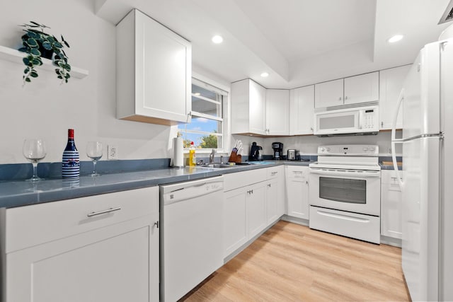 kitchen with white cabinetry, white appliances, and light hardwood / wood-style flooring