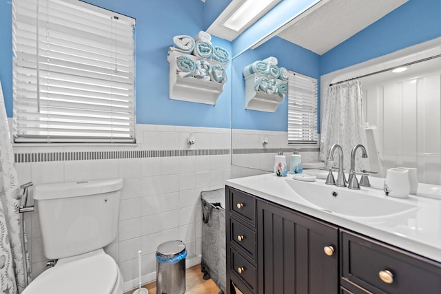 bathroom with vanity, tile walls, and toilet