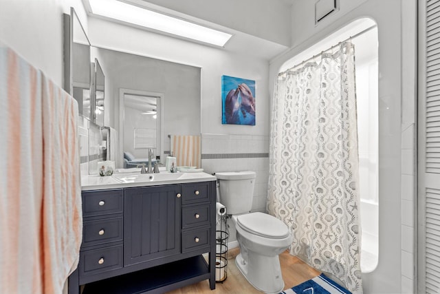 bathroom with wood-type flooring, toilet, tile walls, and vanity