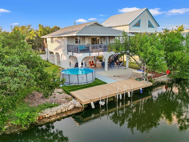 rear view of house with a pool side deck with water view