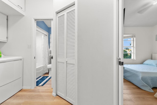 clothes washing area with cabinets, light hardwood / wood-style flooring, and washer / clothes dryer