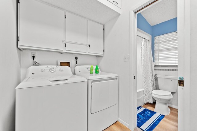 washroom featuring light hardwood / wood-style floors, independent washer and dryer, and a textured ceiling