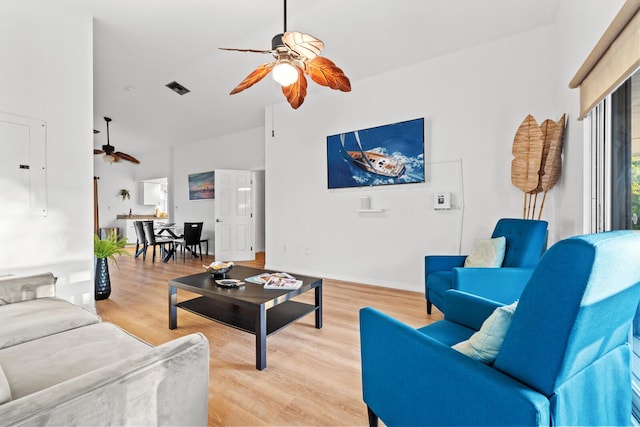 living room with ceiling fan, electric panel, a high ceiling, and light wood-type flooring