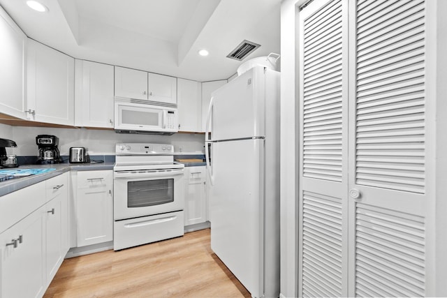 kitchen featuring a raised ceiling, white cabinets, white appliances, and light hardwood / wood-style floors