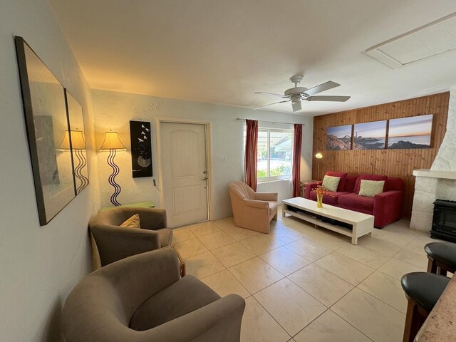 tiled living room with ceiling fan and wooden walls