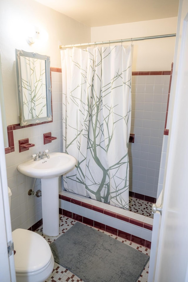 bathroom with tile patterned floors, toilet, curtained shower, and tile walls