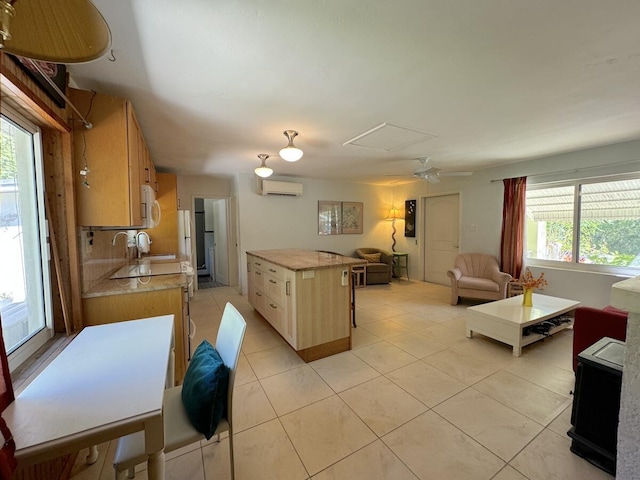 kitchen featuring light brown cabinetry, light tile patterned floors, an AC wall unit, and a kitchen island