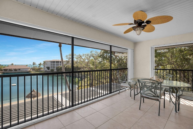 sunroom with a water view and ceiling fan