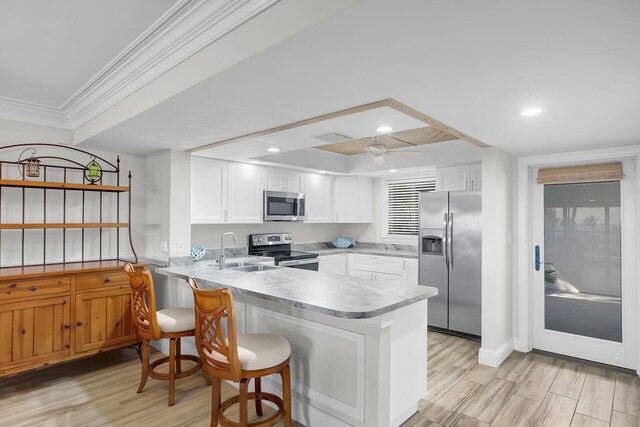 kitchen featuring stainless steel appliances, white cabinetry, sink, and kitchen peninsula