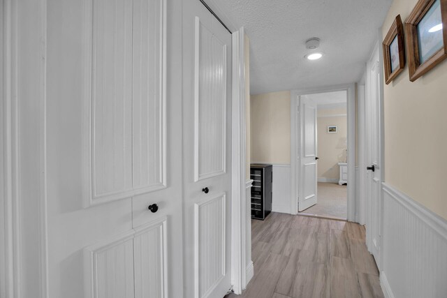 corridor featuring a textured ceiling and light hardwood / wood-style flooring