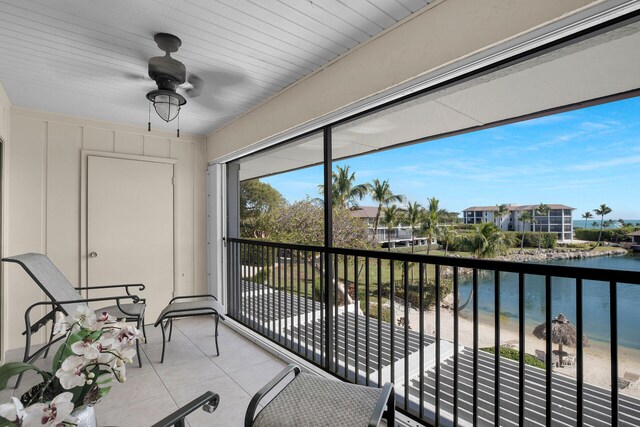 balcony featuring a view of the beach, ceiling fan, and a water view