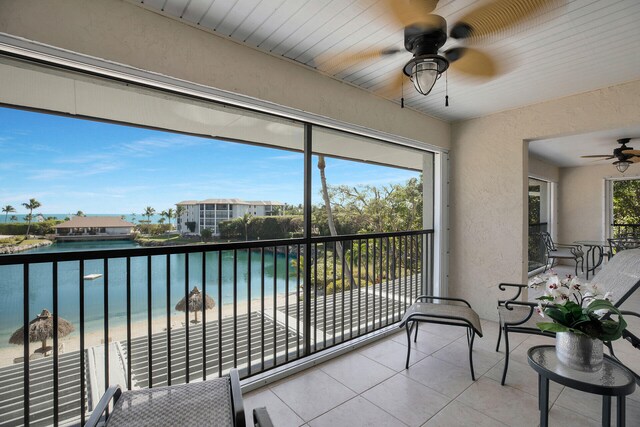 sunroom featuring a wealth of natural light, a beach view, ceiling fan, and a water view