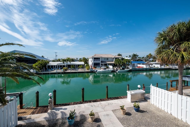 dock area with a water view, fence, and a residential view