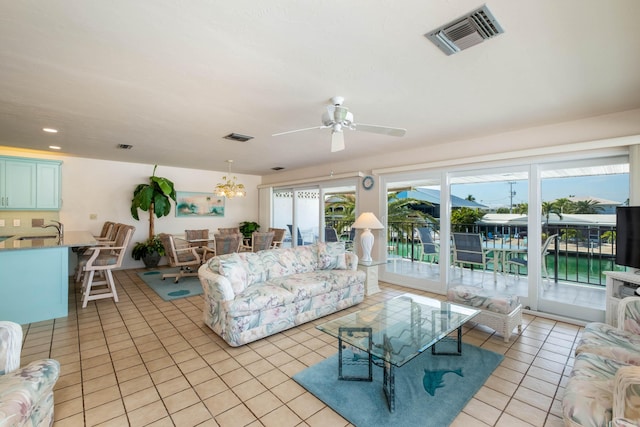 tiled living room featuring ceiling fan with notable chandelier and sink