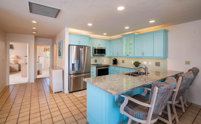 kitchen with appliances with stainless steel finishes, tasteful backsplash, sink, a kitchen breakfast bar, and kitchen peninsula