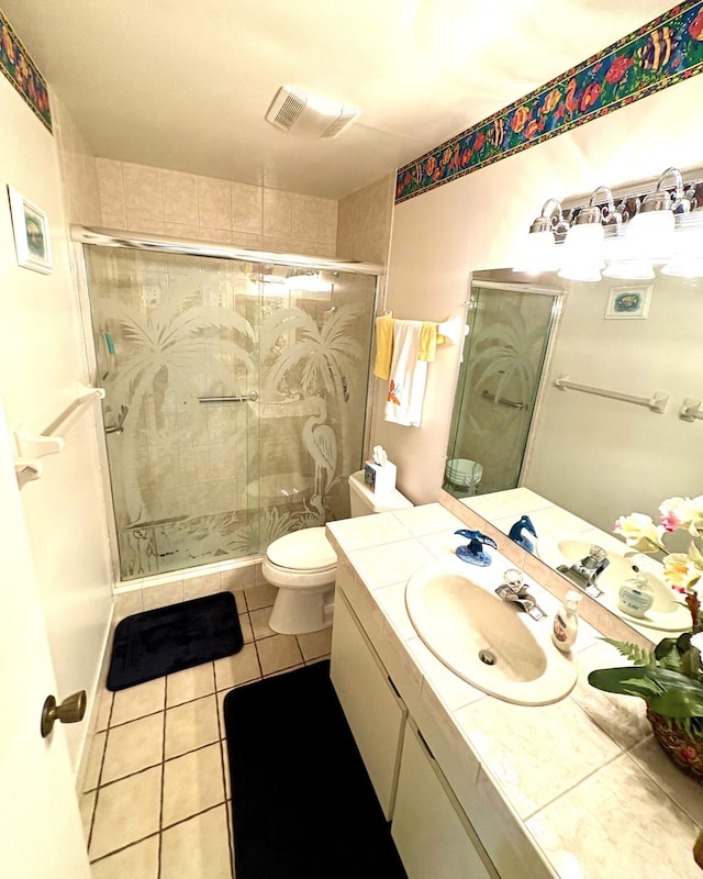 bathroom featuring tile patterned flooring, vanity, walk in shower, and toilet