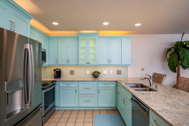 kitchen with appliances with stainless steel finishes, sink, light tile patterned floors, and decorative backsplash