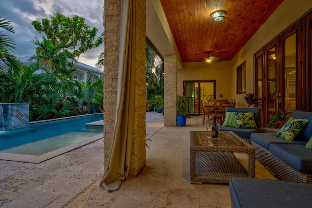 pool at dusk featuring an outdoor living space and a patio