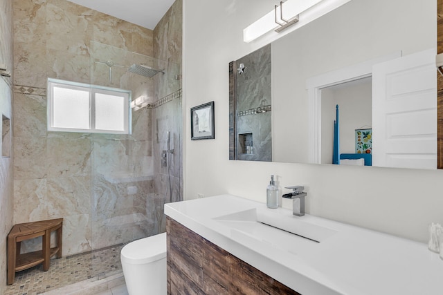 bathroom featuring tiled shower, vanity, and toilet