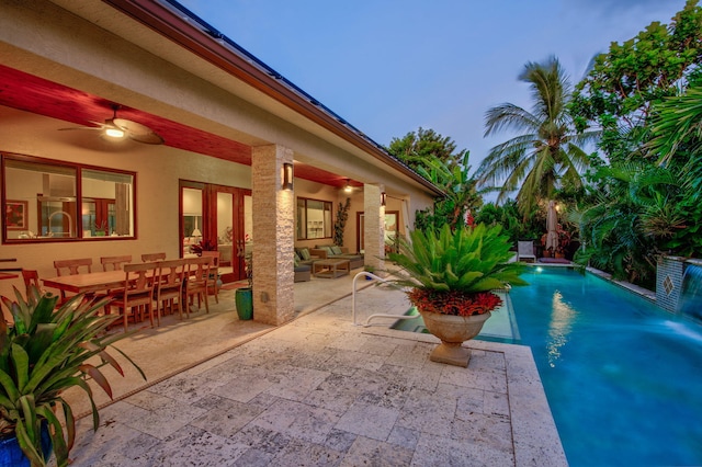 pool at dusk featuring an outdoor hangout area, a patio area, and ceiling fan