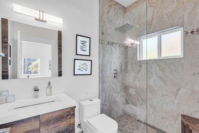 bathroom featuring vanity, a tile shower, and toilet