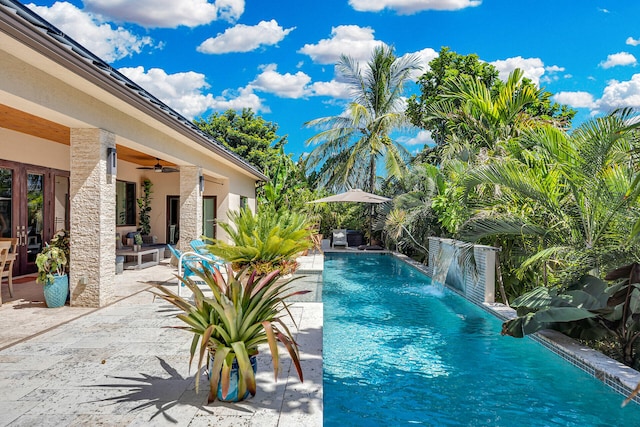 view of swimming pool featuring pool water feature, ceiling fan, outdoor lounge area, and a patio