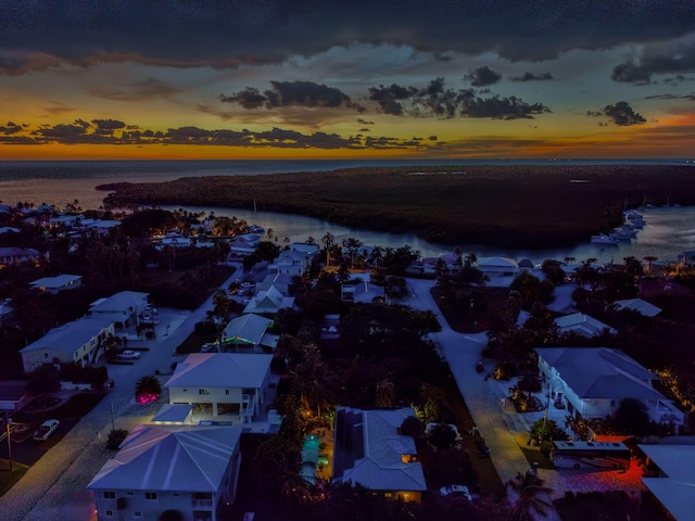 aerial view at dusk featuring a water view